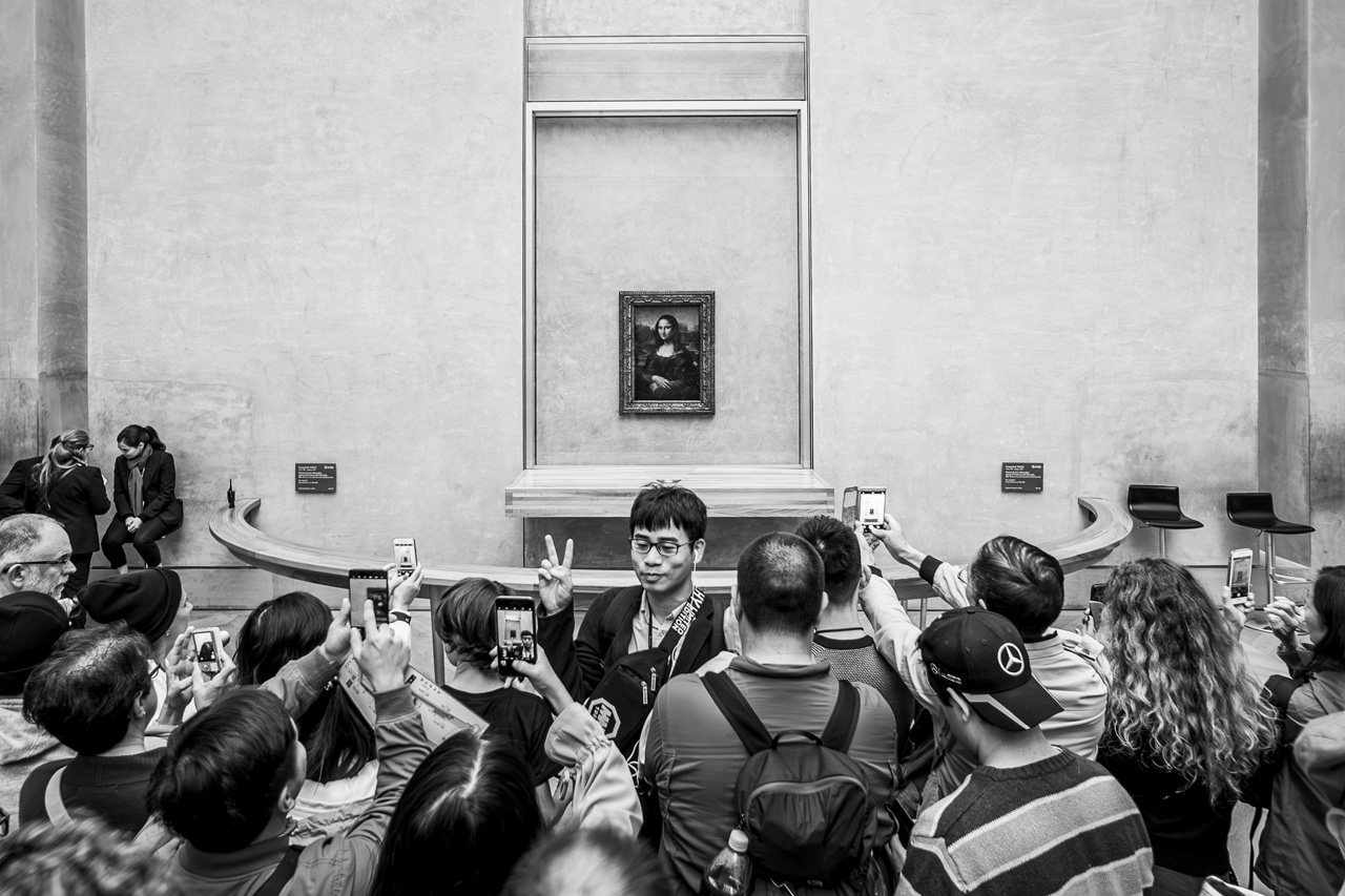 Multitud frente a la Mona Lisa en el Louvre, fotografiándola con sus móviles