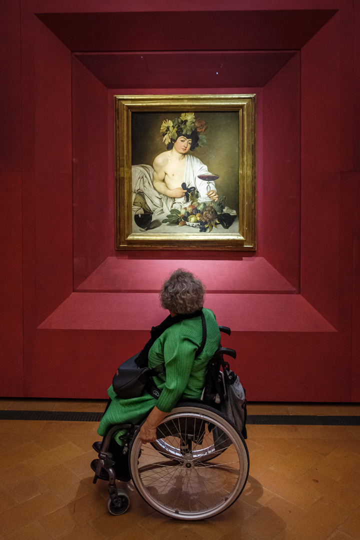 Mujer en silla de ruedas contemplando el Baco de Caravaggio