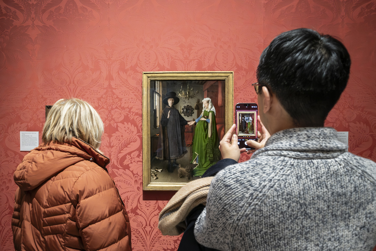 Dos visitantes observando El Matrimonio Arnolfini de Jan van Eyck