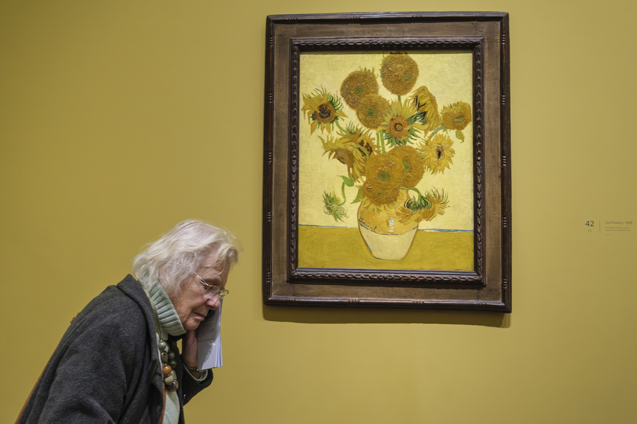 Mujer mayor caminando frente a Los Girasoles de Van Gogh