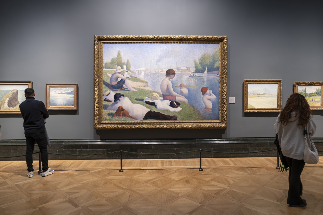 Dos visitantes solos frente a Un baño en Asnières de Seurat
